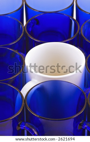 White coffee mug amongst blue glass mugs - vertical format