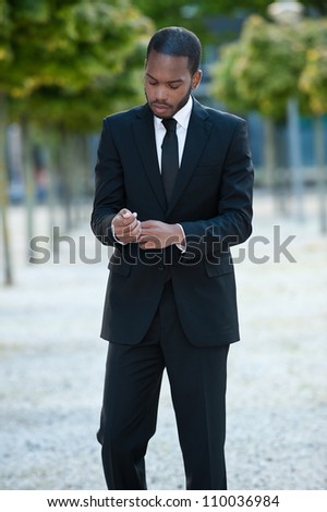 Handsome African American male fashion model adjusting his business suit.