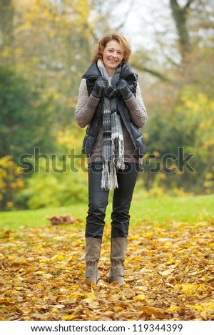 European woman in autumn. Walking on yellow leaves and smiling