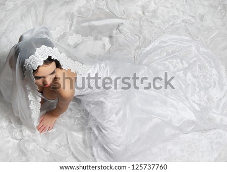 Elegant bride sitting on the floor with long white lace wedding dress