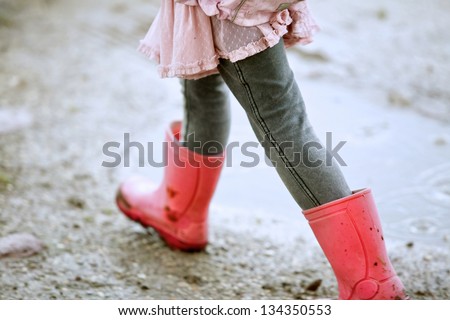 Close up little girl walking outdoors with red boots
