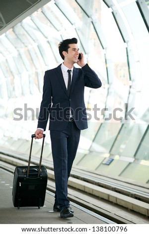 Portrait of a handsome businessman walking on train station platform and talking on the phone