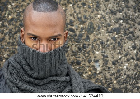 Close up portrait of an african american male fashion model with gray scarf covering face