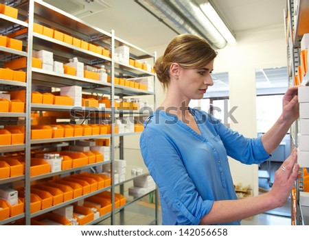 Portrait of a young female pharmacist looking for medicine on shelves