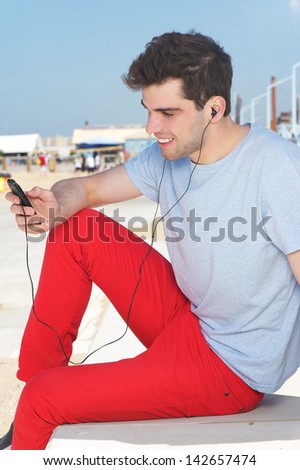 Close up portrait of a happy young man listening to music on mp3 player
