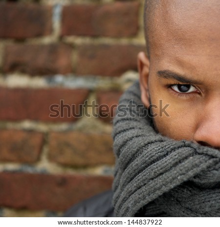 Half face portrait of an attractive male fashion model with scarf covering face