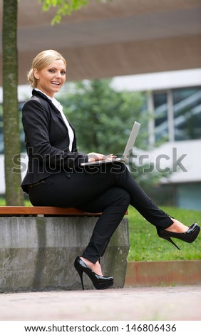Portrait of a beautiful business woman working with laptop in park
