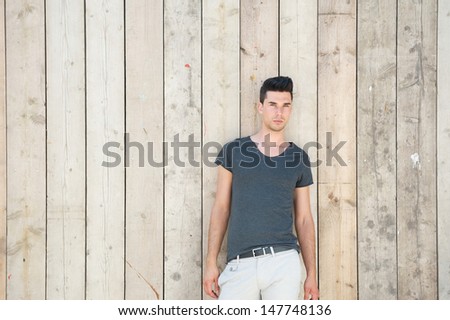 Portrait of an attractive male fashion model standing against wooden wall