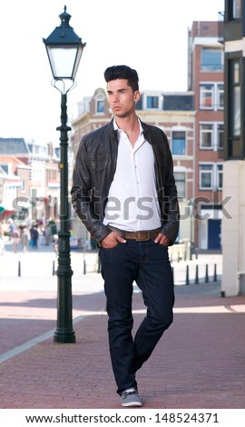 Portrait of a handsome young man walking outdoors in black leather jacket