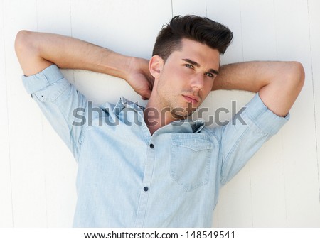 Closeup portrait of a handsome male fashion model with arms raised behind head
