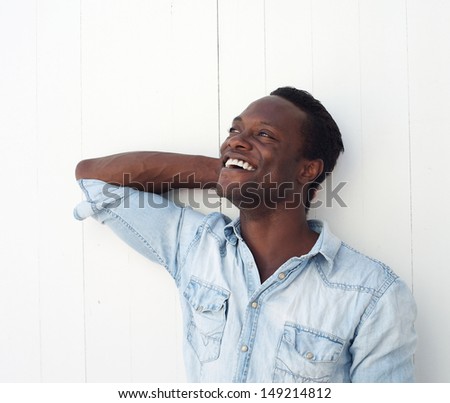 Portrait of a happy young black man laughing outdoors against white background