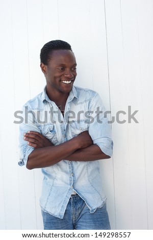 Portrait of an attractive black man with arms crossed, standing against white background outdoors