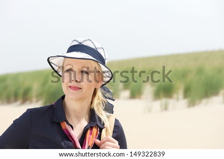 Closeup portrait of an older woman standing at the beach with hat