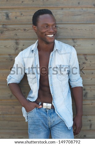 Portrait of a young black man smiling against brown background