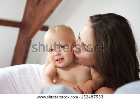Closeup portrait of a happy mother kissing cute baby