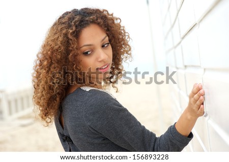 Portrait of a beautiful young woman with hand on wall and looking over shoulder