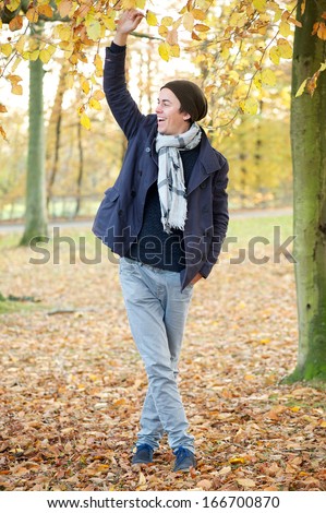 Full body portrait of a young man relaxing outdoors on an Autumn day