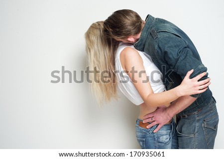 Portrait of a young man kissing blond female against white background
