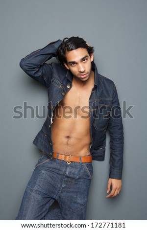 Close up portrait of a sexy young man with open shirt posing against gray background