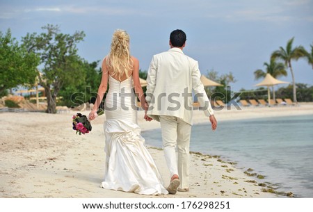 Rear view portrait of husband and wife newlyweds walking on beach together