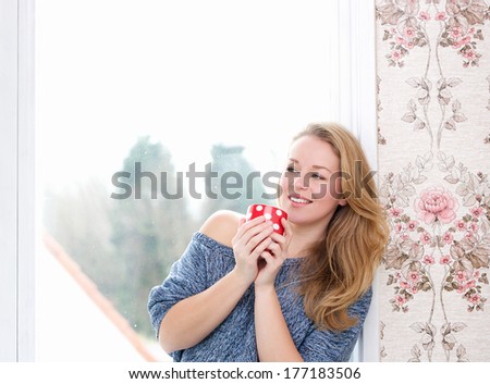 Close up portrait of a young woman relaxing by window with a cup of tea