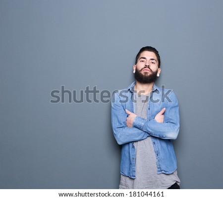 Close up portrait of a cool young guy posing on gray background with arms crossed