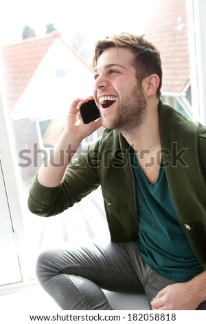 Close up portrait of a young man smiling and talking on mobile phone