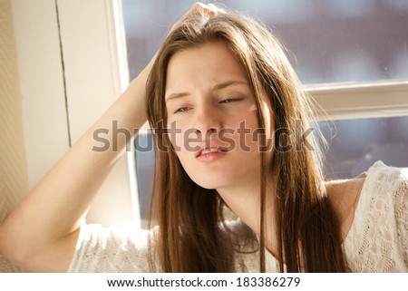 Close up portrait of a young woman relaxing indoors by window