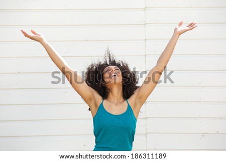 Portrait of a young woman looking up with arms outstretched