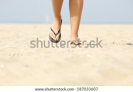 Close up low angle front view of woman walking on beach with flip flops