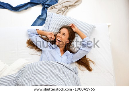 Close up portrait of a smiling woman awake in bed - from above