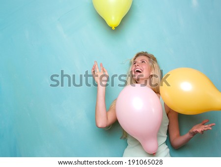 Portrait of a happy young blond woman smiling and playing with balloons