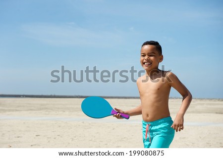 Portrait of a smiling little boy playing paddle ball at the beach