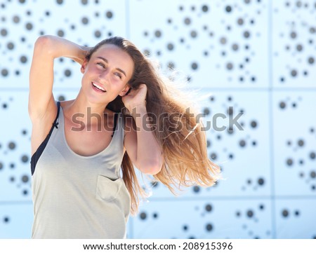 Portrait of a carefree young woman posing with hands in hair
