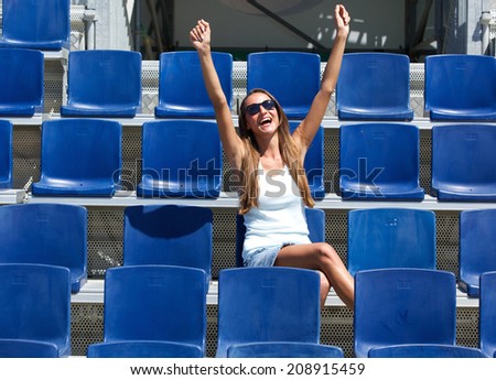 Young woman cheering with arms raised in stadium