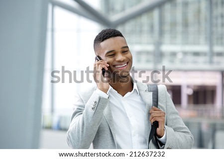 Close up portrait of a handsome young black man smiling with cellphone
