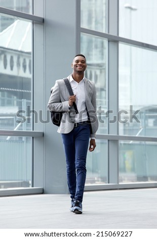 Full length portrait of a handsome young man walking at station with bag
