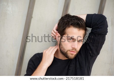 Close up portrait of an attractive male fashion model posing with hands behind head