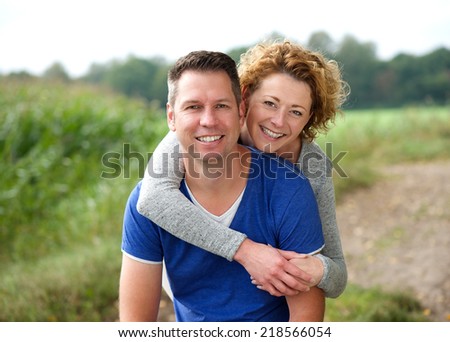 Close up portrait of a smiling woman hugging her boyfriend outdoors