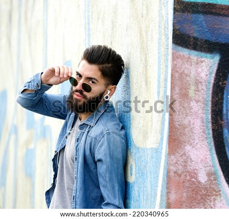 Close up portrait of a cool guy with sunglasses listening to music with earphones
