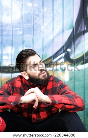 Close up portrait of a cool guy with beard and piercings sitting outdoors