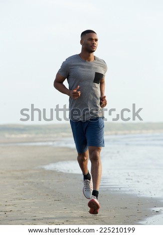 Young black man running on beach to keep fit
