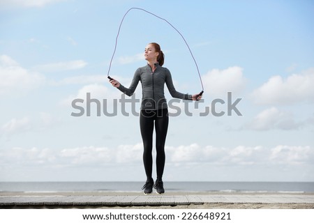Healthy young woman with jump rope at the beach