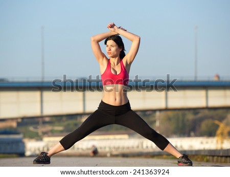 Portrait of a beautiful young woman wearing gym clothes and stretching muscles