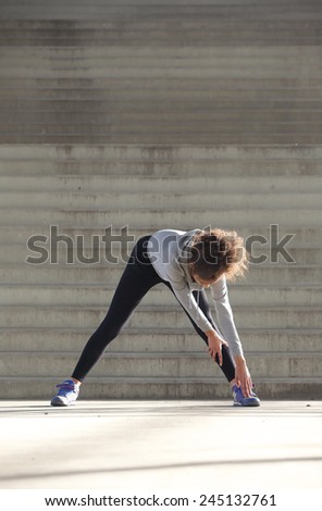 Portrait of a young woman bending down stretching leg muscles