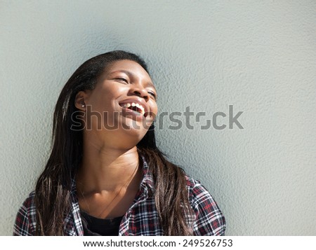 Close up portrait of a happy young black woman laughing outdoors