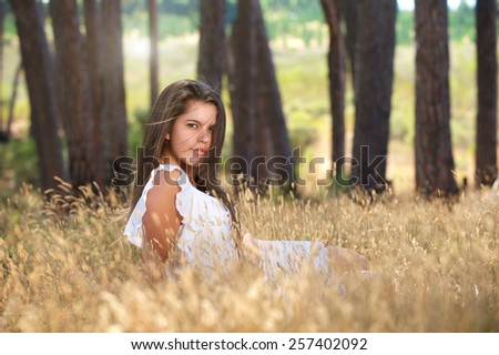 Portrait of a sensual young woman sitting in a field in nature