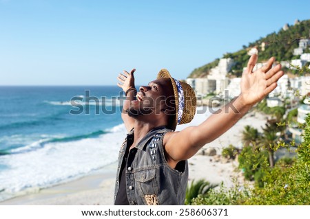 Portrait of a happy african american man with arms outstretched by the beach