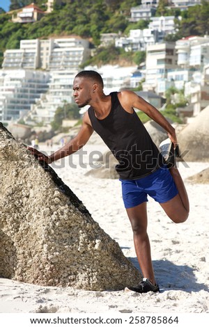 Portrait of a handsome young sports man stretching work out at the beach