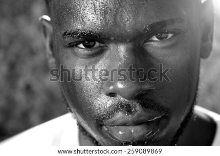 Close up black and white portrait of a young man sweating with intense look of face